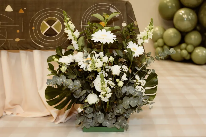 White floral arrangement beside sage balloons